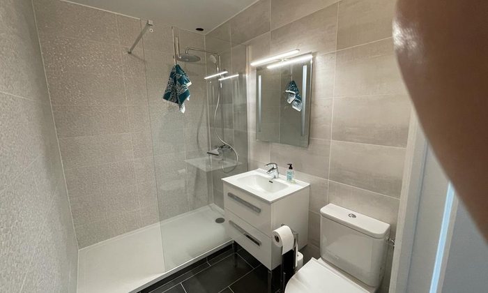 Salle de bain accessible avec douche et meuble vasque